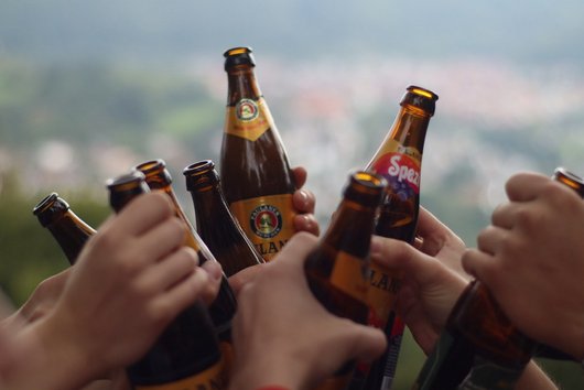 Mehrere Leute stoßen mit Bier und Spezi an